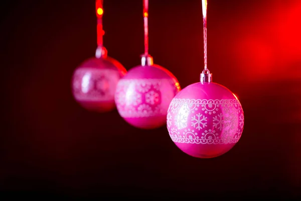 Παραδοσιακά ροζ μπάλες Χριστούγεννα σε μαύρο φόντο με κόκκινο πίσω φως. — Φωτογραφία Αρχείου