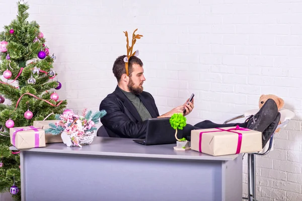 Frilansare i hjorthorn och en kostym som arbetar på en bärbar dator kvällen före jul, en arbetsnarkoman. — Stockfoto