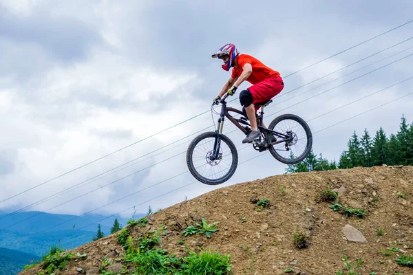 Professzionális kerékpáros jön le a hegyről egy mountain bike, downhill. — Stock Fotó