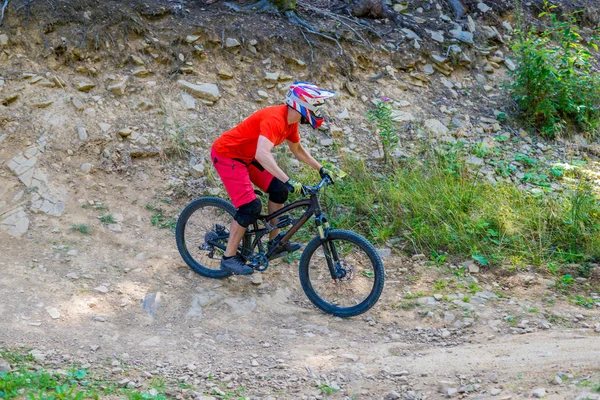 Professional Cyclist Riding the Bike on the Rocky Trail.