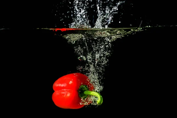 Red fresh paprika splash in water on a black background. — Stock Photo, Image