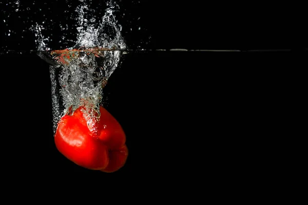 Červená čerstvá paprika splash ve vodě na černém pozadí. — Stock fotografie