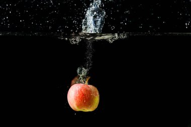 ile su hareketi resim siyah bir zemin üzerine kırmızı elma.