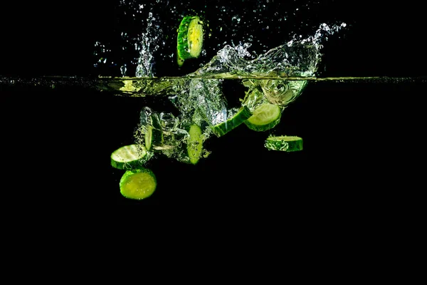 Шматочки огірка падають у воду . — стокове фото