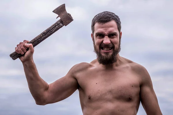 Hombre barbudo con un hacha de hierro contra el cielo . — Foto de Stock