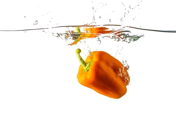 Болгарский оранжевый перец бросили в воду на белом фоне — стоковое фото