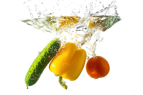Сочный помидор, перец, огурец падают в воду с брызгами воды, изолированные на белом фоне. Концепция здорового питания, питания . — стоковое фото