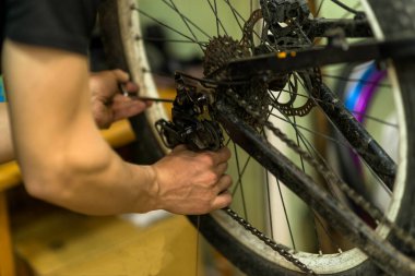 Bisiklet tamircisi bisiklet tekerleğini tamir ediyor, yakın plan. Bisiklet atölyesi.