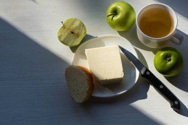 Lezzetli kahvaltı: Ahşap bir masada aromatik çay, tereyağı ve yeşil elma. Sağlıklı yeme kavramı.