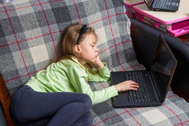 Şirin kız evdeki kanepede dizüstü bilgisayar kullanıyor. Uzaktan çalışma kavramı.