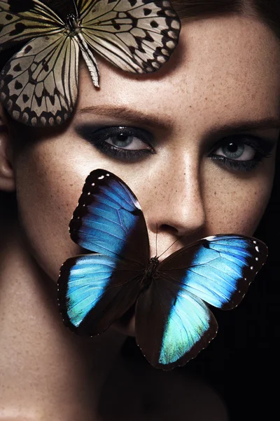 Tutup potret gadis dengan riasan yang indah. Kupu-kupu eksotis biru. Wajah bintik-bintik Stok Lukisan  