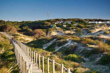 Praia Guincho sahilinde kum tepeleri ve gün batımında kıyı şeridi.