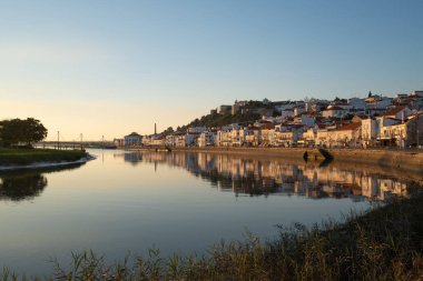 Gün batımında Sado nehrinin diğer tarafından Alcacer 'in Sal şehir manzarası