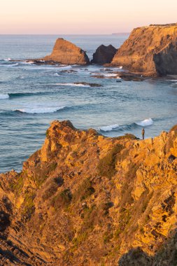 Woman on a cliff at Praia de Odeceixe in Costa Vicentina, Portugal