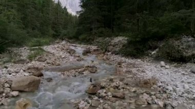 Dolomitler, İtalyan Alpleri ve arka planında Furchetta Dağı olan bir nehir üzerindeki hava aracı manzarası.