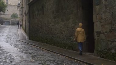 Santiago de Compostela, İspanya 'da yağmurlu bir günde sarı ceketli bir kadın gezgin.