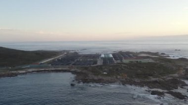 Galiza, İspanya 'da gün batımında karadaki bir deniz çiftliğinin insansız hava aracı manzarası