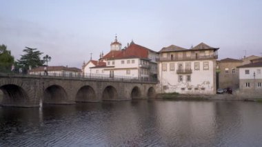 Şafak vakti Portekiz 'de güzel bir yansımayla Tamega nehri ile köprü ve kilise manzarası.