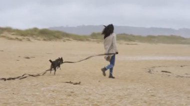 Kız sahilde topla oynayıp eğleniyor.