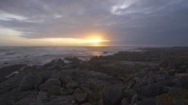 Güzel gün batımı kaya plajı manzarası. İspanya 'da okyanusu vuran dalgalarla huzur verici.