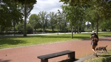 Beyaz kadın köpekle birlikte Chaves, Portekiz 'de ağaçlı bir parkta yürüyor.