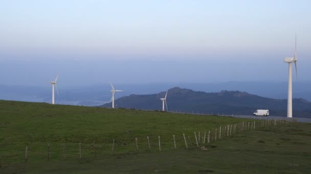西班牙赫贝伊拉湾的风力涡轮机可再生能源在日落时分与蓝天和绿色山水相映成趣 — 图库视频影像