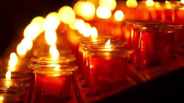 祈りの教会で暗い環境の雰囲気の中で炎をクローズアップした赤いキャンドル — ストック動画