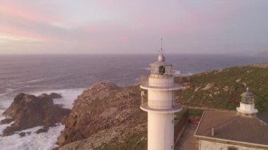 İspanya 'da, gün batımında Pembe bulutlu Cape Tourinan Deniz Feneri' nin inanılmaz hava aracı manzarası