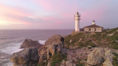 Fotoğrafçı İHA hava görüntüsü İspanya 'da, güneş batarken Cape Tourinan Deniz Feneri' nin deniz manzarası görüntüsünü çekiyor.