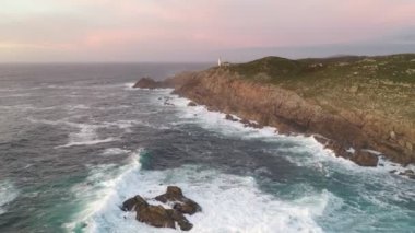 İspanya 'da, gün batımında Pembe bulutlu Cape Tourinan Deniz Feneri' nin inanılmaz hava aracı manzarası