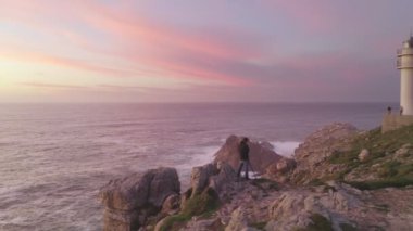Fotoğrafçı İHA hava görüntüsü İspanya 'da, güneş batarken Cape Tourinan Deniz Feneri' nin deniz manzarası görüntüsünü çekiyor.