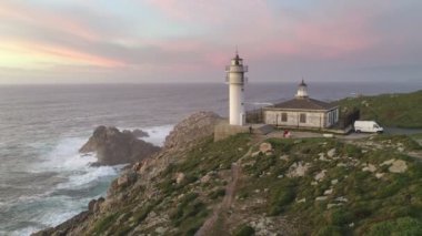 İspanya 'da, gün batımında Pembe bulutlu Cape Tourinan Deniz Feneri' nin inanılmaz hava aracı manzarası