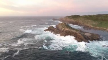 İspanya 'da, gün batımında Pembe bulutlu Cape Tourinan Deniz Feneri' nin inanılmaz hava aracı manzarası