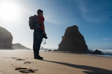 Man taking photos in Santa Cruz beach, in Portugal clipart