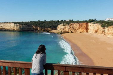 Portekiz, Algarve 'de gün batımında Nossa Senhora da Rocha plajına bakan bir kadın.