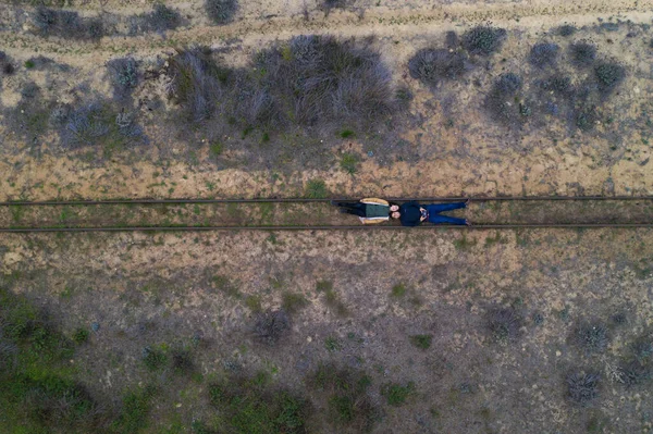 Couple lying on a rail track drone aerial top view on a desert landscape