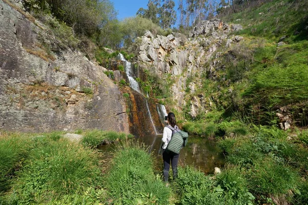 Woman girl adventurer traveler photographing a waterfall with a phone in Vila de Rei, Portugal