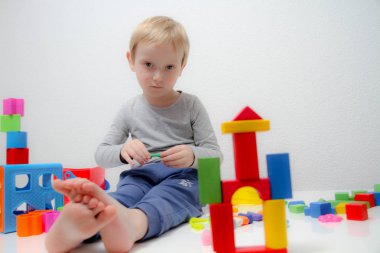Küçük çocuk üç yaşında masada oturur ve plas ile çalış