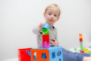 Küçük çocuk üç yaşında masada oturur ve plas ile çalış