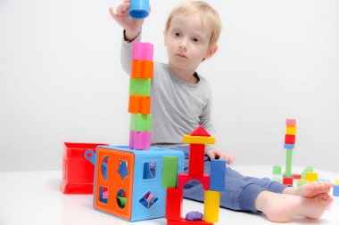 Küçük çocuk üç yaşında masada oturur ve plas ile çalış