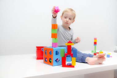 Küçük çocuk üç yaşında masada oturur ve plas ile çalış