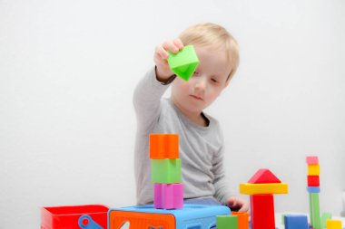 Küçük çocuk üç yaşında masada oturur ve plas ile çalış