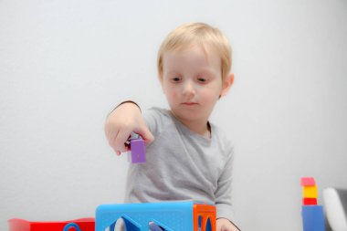 Küçük çocuk üç yaşında masada oturur ve plas ile çalış