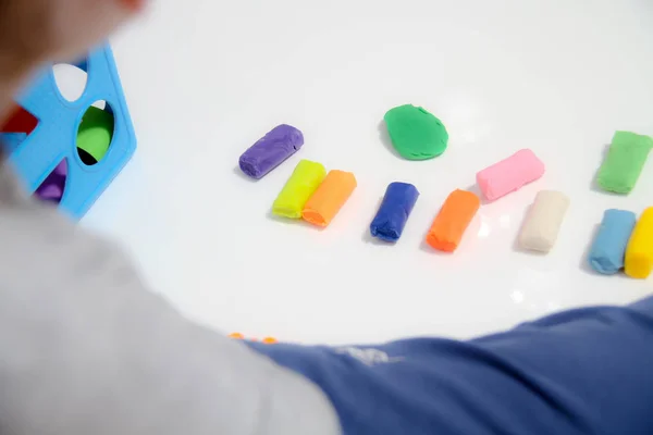 Little boy three years old sits on the table and plays with plas — Stock Photo, Image