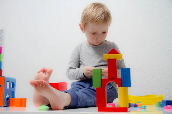Ragazzino di tre anni si siede sul tavolo e gioca con i plas — Foto Stock