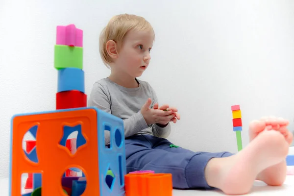 Niño pequeño de tres años se sienta en la mesa y juega con plas —  Fotos de Stock