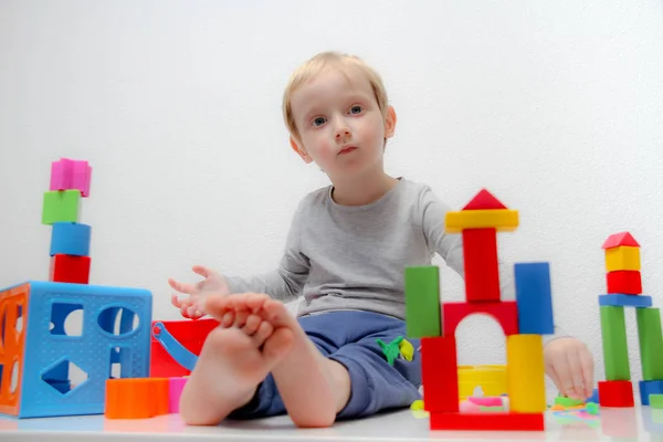 Ragazzino di tre anni si siede sul tavolo e gioca con i plas — Foto Stock