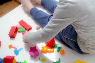 Küçük çocuk üç yaşında masada oturur ve plas ile çalış