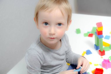 Küçük çocuk üç yaşında masada oturur ve plas ile çalış