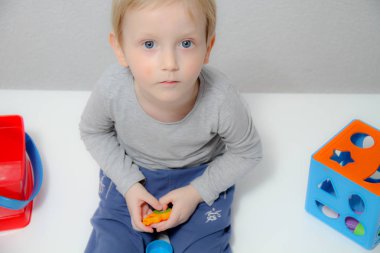 Küçük çocuk üç yaşında masada oturur ve plas ile çalış